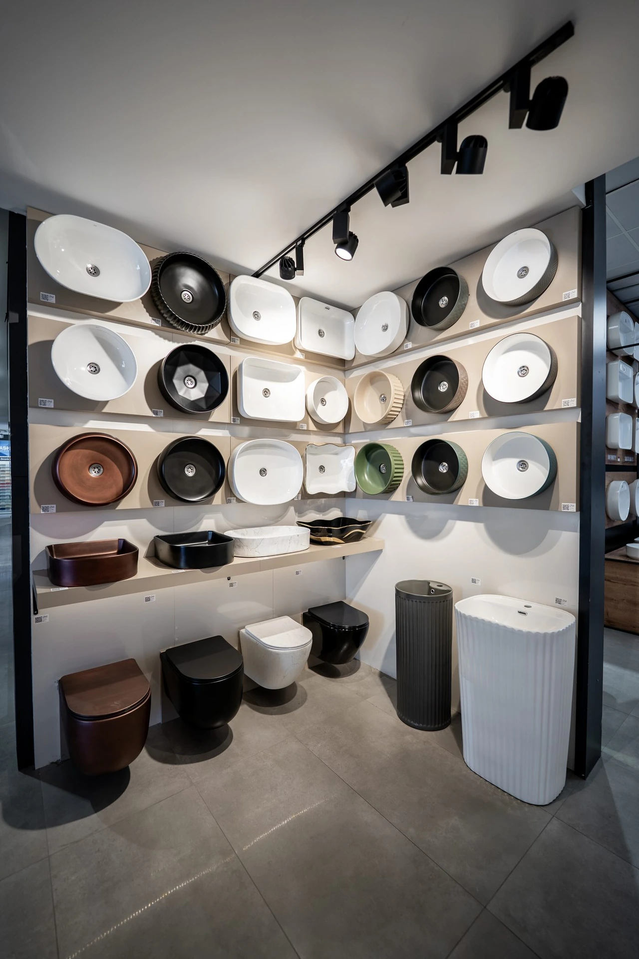 Beyaz, siyah ve renkli çanak lavabolar ile kumanda panellerinin duvar teşhiri